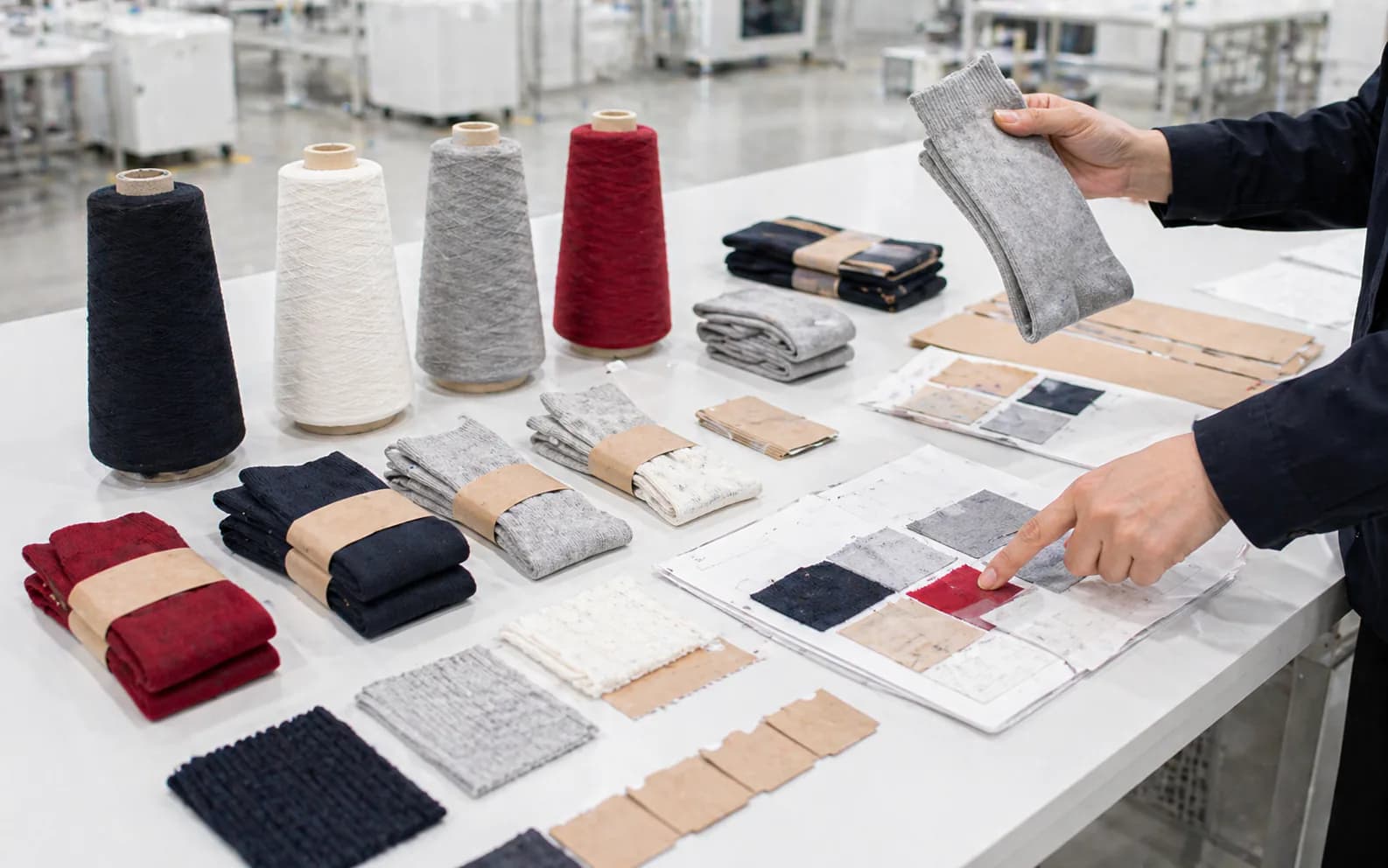 Buyer-facing review desk with sock samples, yarn cones, and packaging references